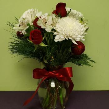Bouquet of red roses and white flowers in a glass vase with a red ribbon