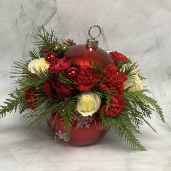 Red ornament with red and white flowers and evergreen sprigs