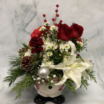 Holiday floral arrangement in a Santa-shaped container with red roses and white lilies