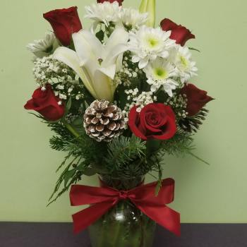 Red roses and white lilies in a glass vase with a red bow
