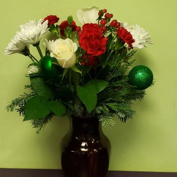 Red and white flowers arranged in a dark vase with green ornaments