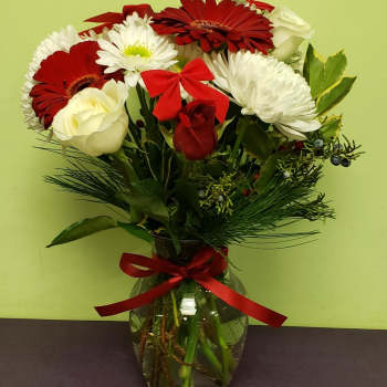 Bouquet of red and white flowers in a glass vase with a red ribbon