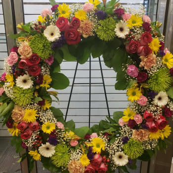 Large circular floral wreath with mixed roses, daisies, and mums