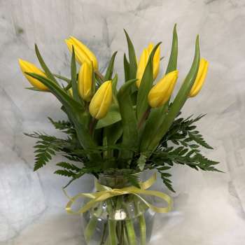 Yellow tulip bouquet in a glass vase with a yellow ribbon