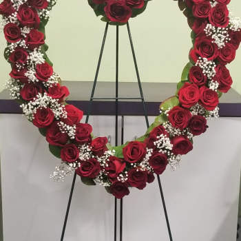 Heart-shaped rose wreath on a black stand