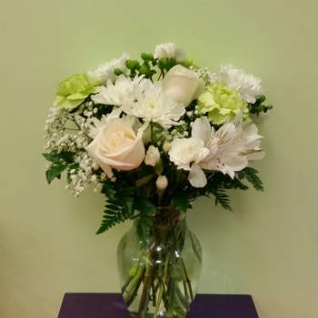 White and pale peach flowers arranged in a clear glass vase
