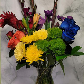 Colorful mixed bouquet in a clear glass vase with roses, chrysanthemums, and lilies