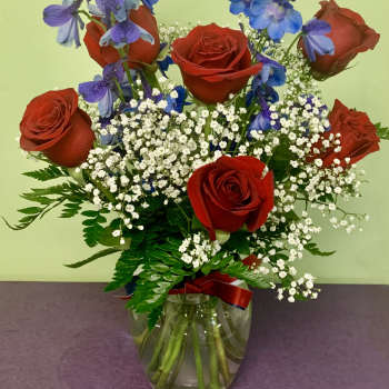 Red roses and blue-purple flowers in a glass vase
