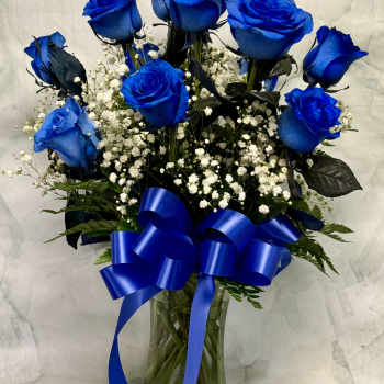 Blue roses in a glass vase with white baby's breath and a blue ribbon