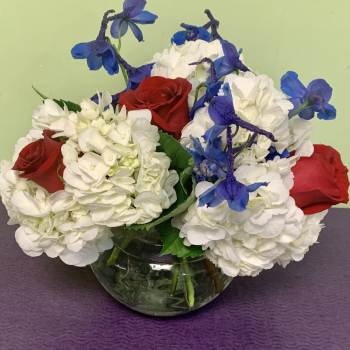 Red roses and white hydrangeas with blue flowers in a glass vase