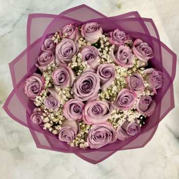Bouquet of lavender roses with white filler flowers wrapped in purple paper