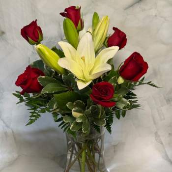Red roses and white lilies arranged in a clear glass vase