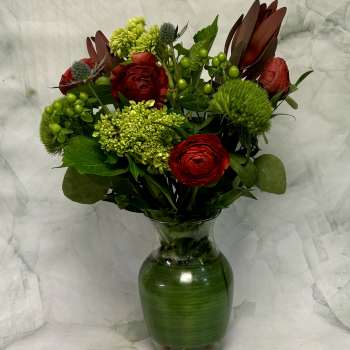 Red and green floral arrangement in a glass vase