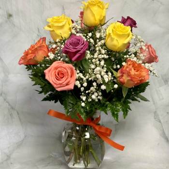 Bouquet of multicolored roses in a glass vase with a ribbon