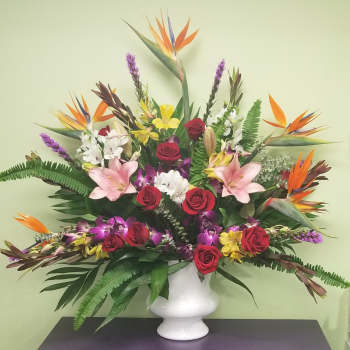 Tropical flower arrangement with roses, lilies, and bird-of-paradise in a white vase