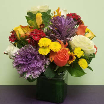 Mixed bouquet in a dark green vase with roses and chrysanthemums