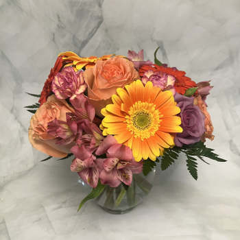 Mixed bouquet of roses, gerbera daisies, and alstroemeria in a glass vase