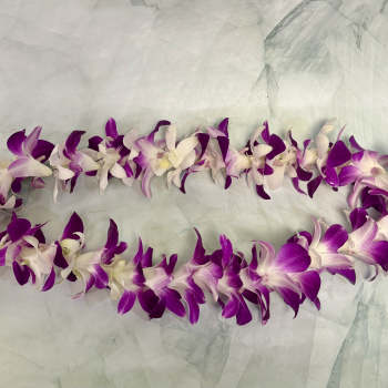 Purple and white orchid lei on a pale fabric background