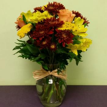 Bouquet of yellow and peach flowers in a glass vase