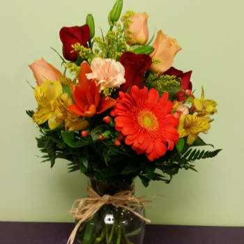 Mixed bouquet of roses, gerbera daisies, lilies, and alstroemeria in a glass vase