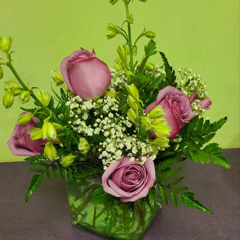 Pink roses and white filler flowers in a green glass vase