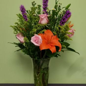 Bouquet of orange lilies and pink roses in a clear glass vase