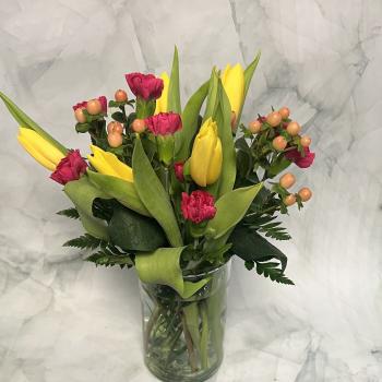 Yellow tulips and pink carnations in a clear glass vase