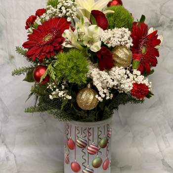 Red and white floral arrangement in a decorated cylindrical container