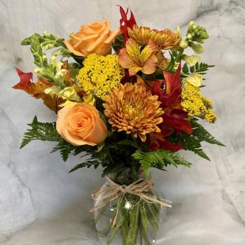 Bouquet of orange roses and yellow chrysanthemums in a glass vase