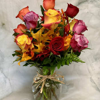 Mixed roses in a glass vase with autumn leaves