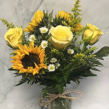 Bouquet of yellow roses and sunflowers in a glass vase