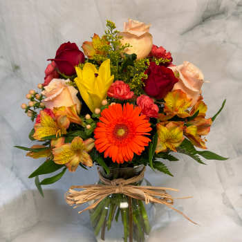Mixed bouquet of roses, gerbera daisies, and alstroemeria in a glass vase