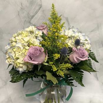 Bouquet of pale hydrangeas and lavender roses in a glass vase