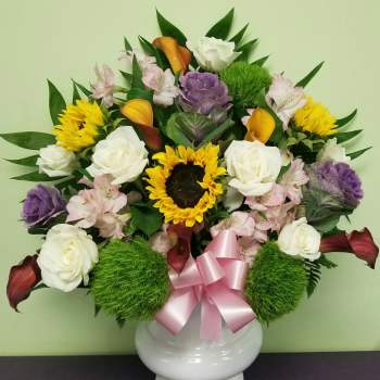 Mixed bouquet in a white vase with roses, sunflowers, and calla lilies
