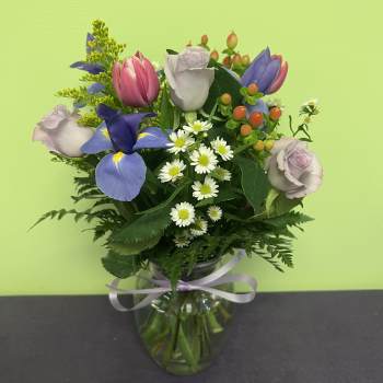 Mixed bouquet of roses, tulips, and daisies in a glass vase