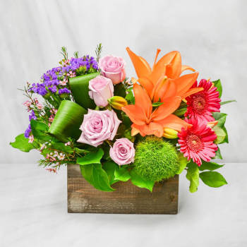 Colorful flower arrangement in a wooden box with roses, lilies, and gerbera daisies