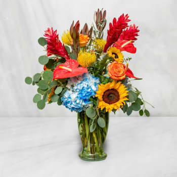 Colorful tropical bouquet in a glass vase with sunflowers and hydrangeas