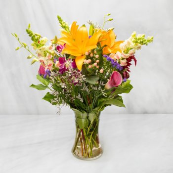 Mixed bouquet with yellow lilies and pink calla lilies in a clear glass vase