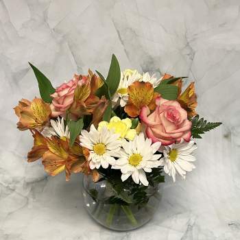 Bouquet of pink roses and white daisies in a round glass vase