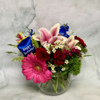 Mixed bouquet in a glass vase with a birthday tag
