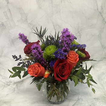 Mixed bouquet of red and orange roses in a clear glass vase