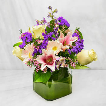 Mixed bouquet of lilies, roses, and daisies in a glass vase