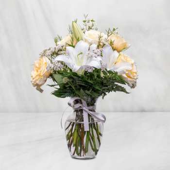 Bouquet of white lilies and pale peach roses in a glass vase
