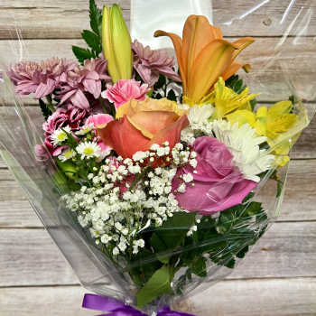 Mixed bouquet with roses, lilies, daisies, and carnations in clear wrap