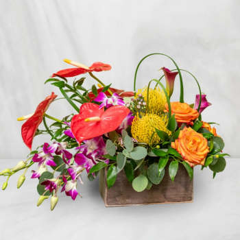 Tropical flower arrangement in a wooden box with red anthuriums and orange roses