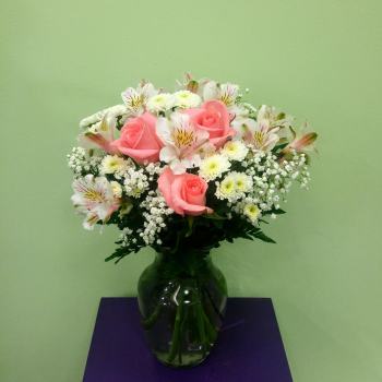Pink roses and white flowers arranged in a glass vase