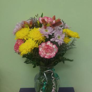Bouquet of yellow chrysanthemums and pink carnations in a glass vase