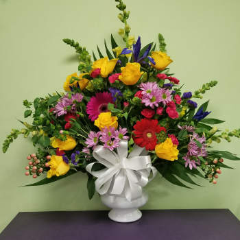 Mixed bouquet in a white vase with a large white ribbon