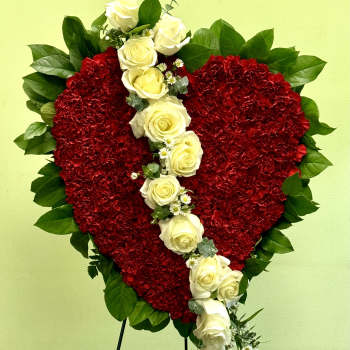 Heart-shaped red floral tribute with white roses on a stand