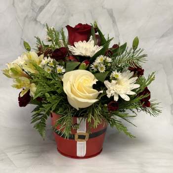 Red and white flower arrangement in a Santa-themed container